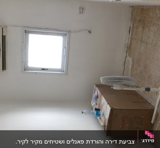 חדר עם קירות צבועים בלבן, מאוורר עומד על קרטון